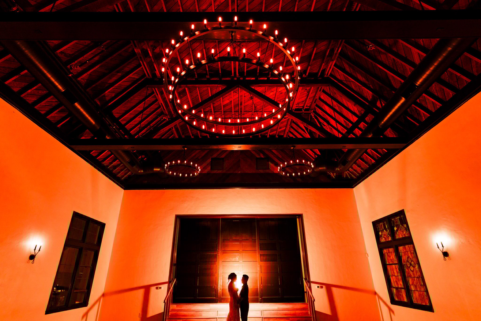 Silhouette of bride and groom with dramatic red lighting and cathedral chandeliers at The Sanctuary