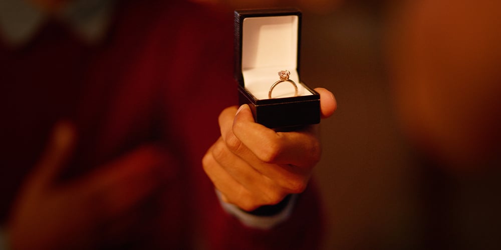 Engagement ring in a box being held by a person.