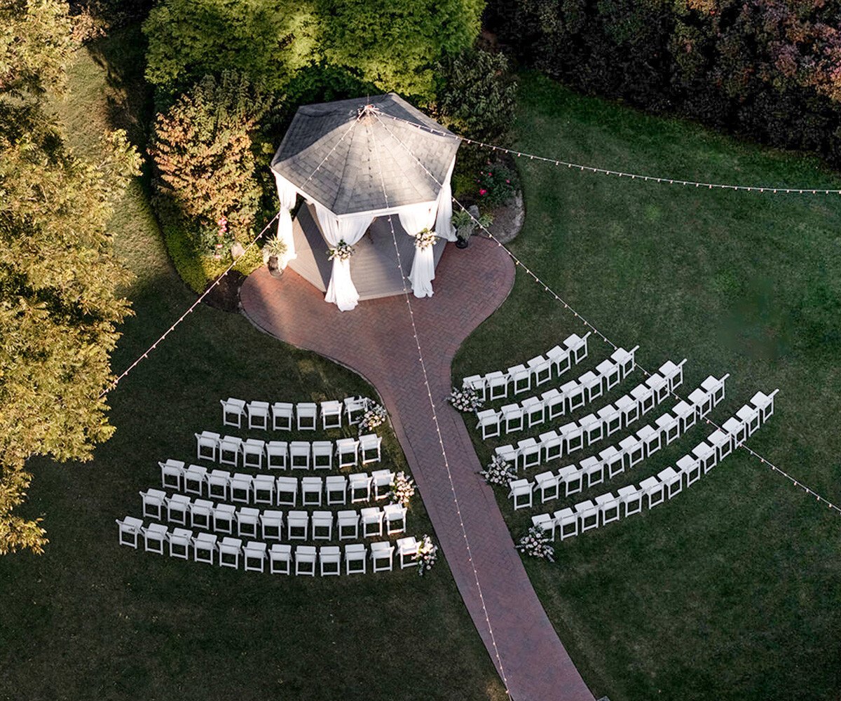 Aerial view of octagonal wedding gazebo with brick walkway and white ceremony chairs arranged in semi-circle pattern