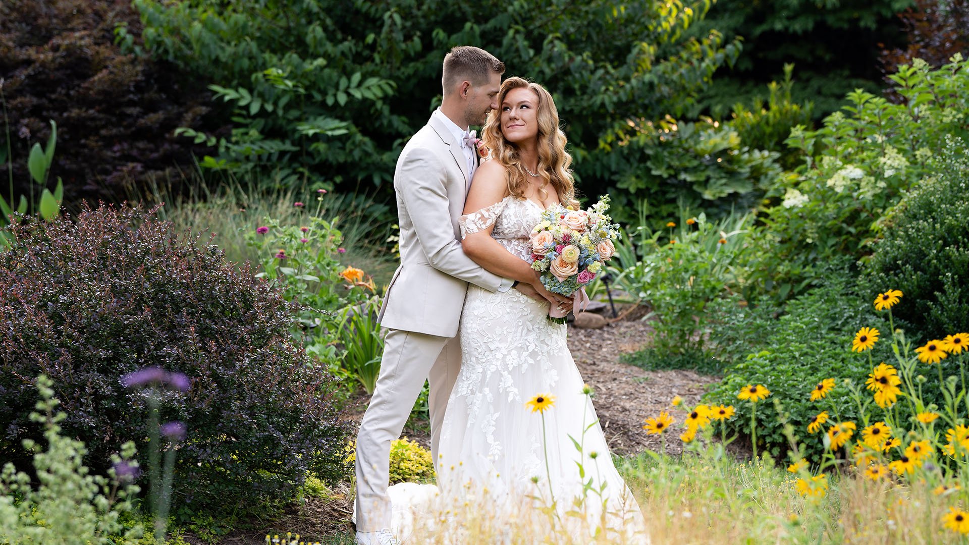 Couple embracing among wildflowers and garden landscape at Alexander Homestead wedding venue in Charlotte