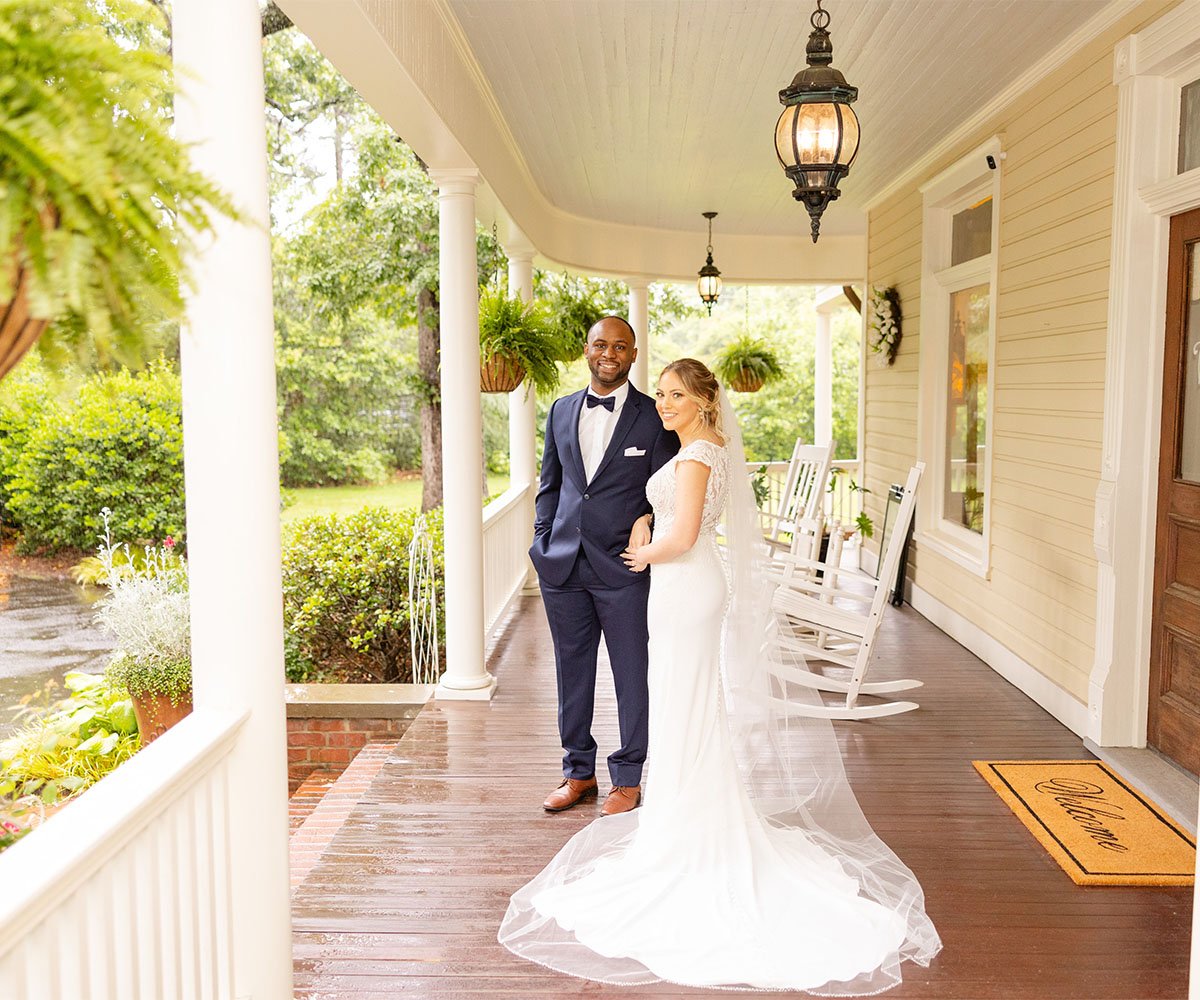 Elegant bride and groom portrait on charming wraparound porch at Alexander Homestead in Charlotte NC with classic white columns,