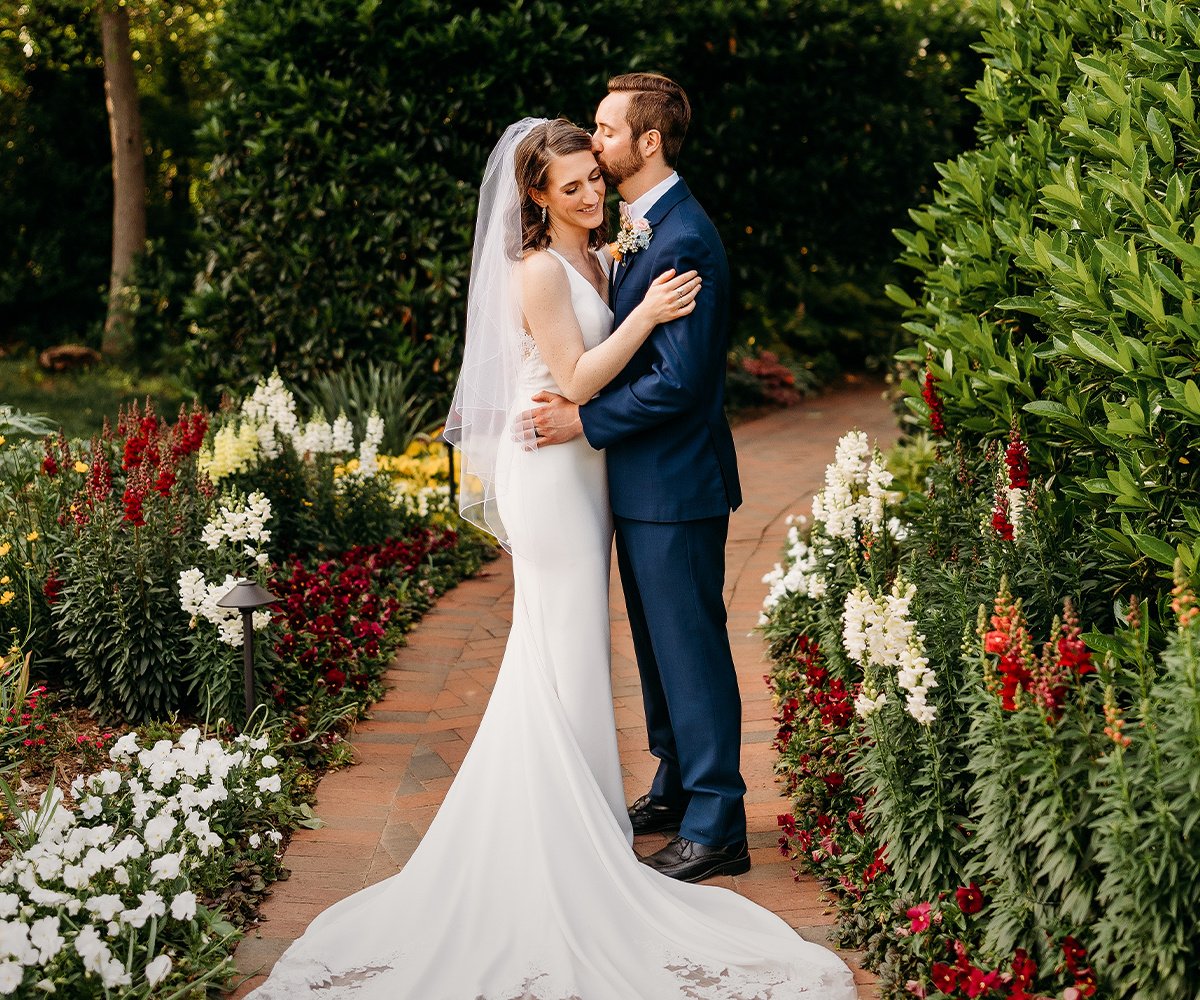 Romantic garden portrait of newlyweds surrounded by vibrant flowers at Alexander Homestead venue in Charlotte NC