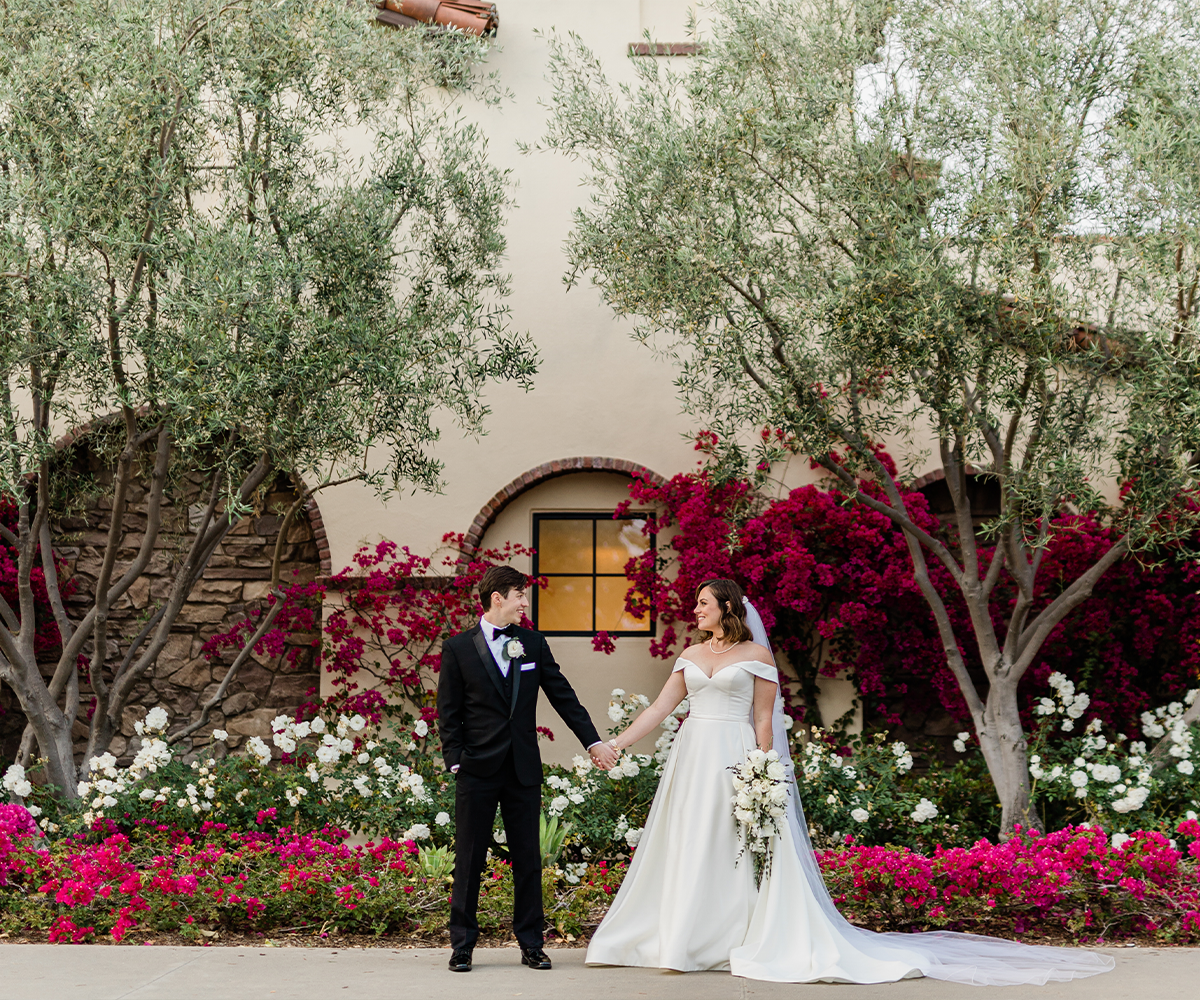 Couple in front of building and bright flowers - Aliso Viejo by Wedgewood Weddings