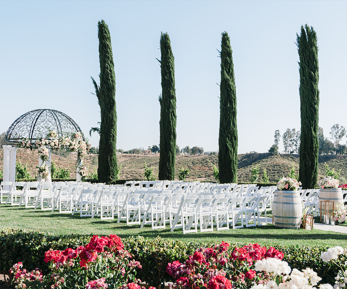 Elegant outdoor ceremony setup with white columns and lush greenery at Avensole Winery