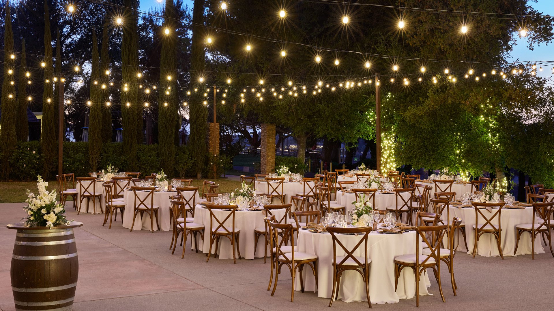 Elegant outdoor reception courtyard at Bel Vino Winery with rustic tables, floral centerpieces, and vineyard backdrop.