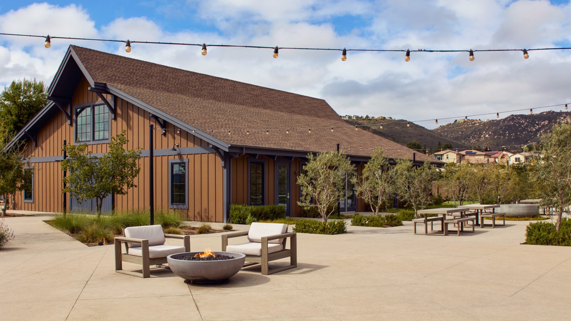 Cozy outdoor patio at Canopy Grove featuring modern firepit seating, rustic barn exterior, and mountain views.