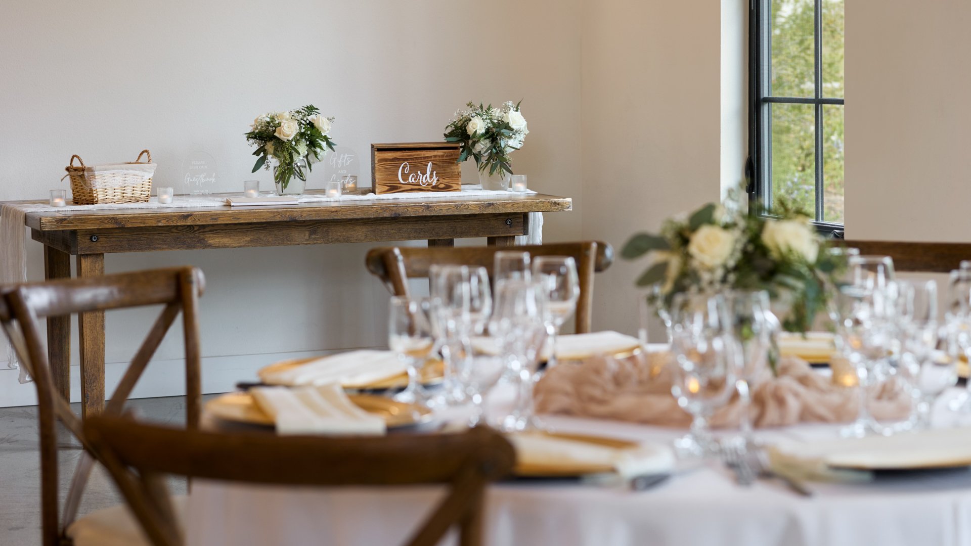 Rustic wood gift and card table decorated with floral arrangements, candles, and signage inside the Canopy Grove wedding reception barn in Escondido, CA.