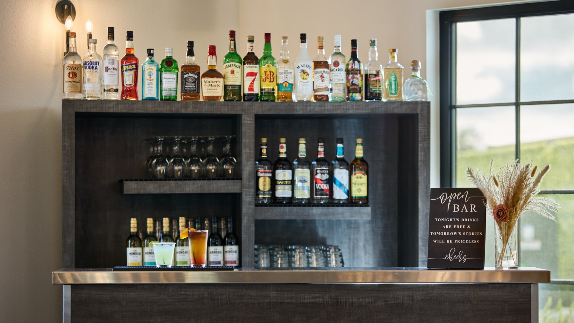 Reception bar with liquor display, open bar sign, and signature cocktails at Canopy Grove wedding barn.