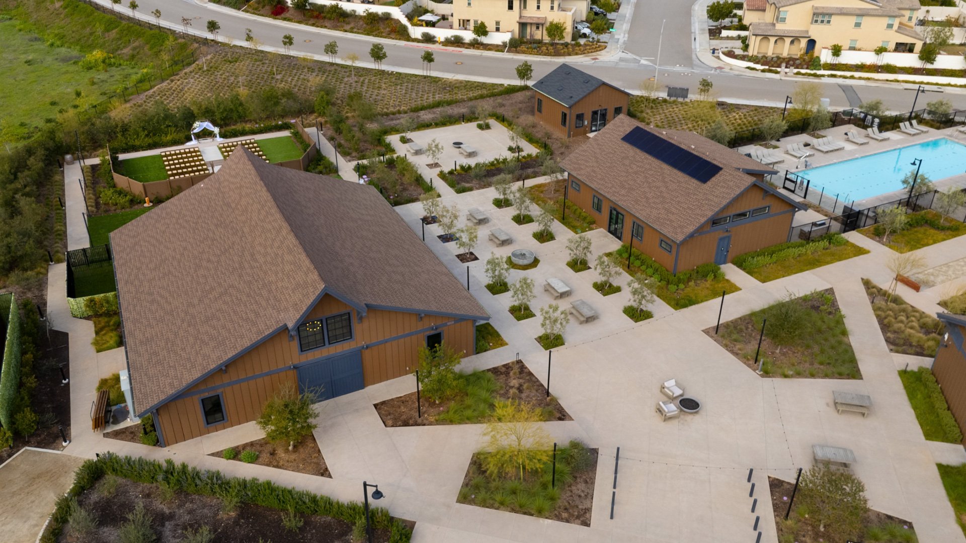 Wide aerial view of Canopy Grove showcasing the ceremony lawn, barn reception hall, and landscaped outdoor courtyards.