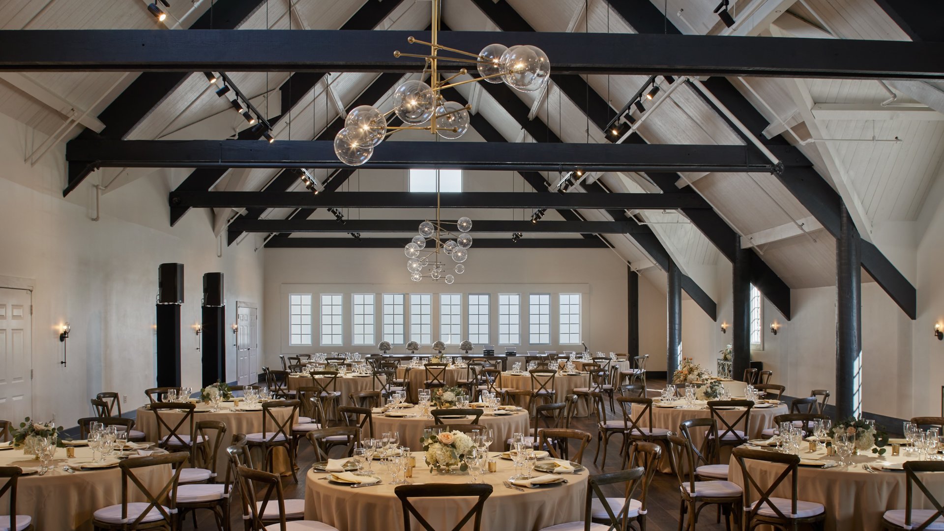 Carlsbad Windmill Loft reception with round tables, neutral linens, and floral centerpieces.