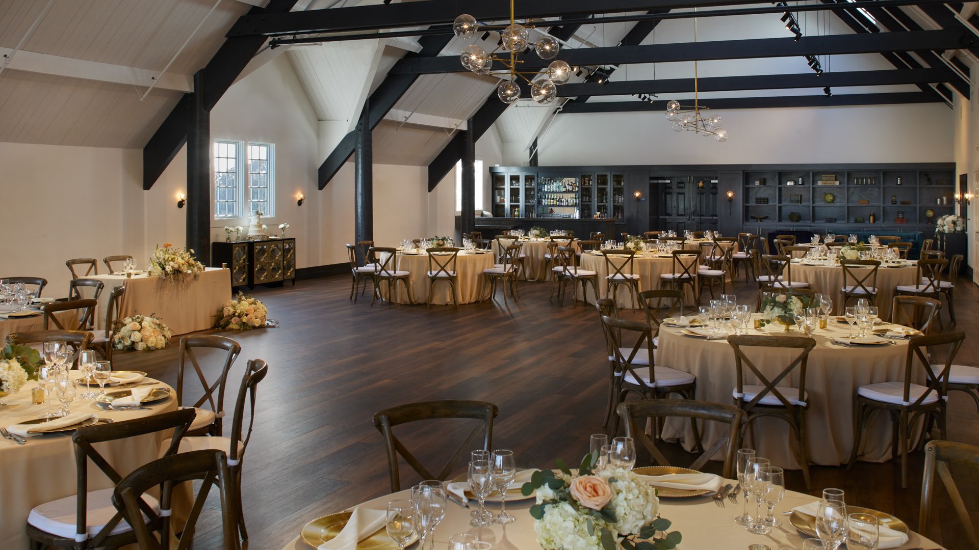Stylish Carlsbad Windmill Loft reception hall with wooden cross-back chairs and gold accents.