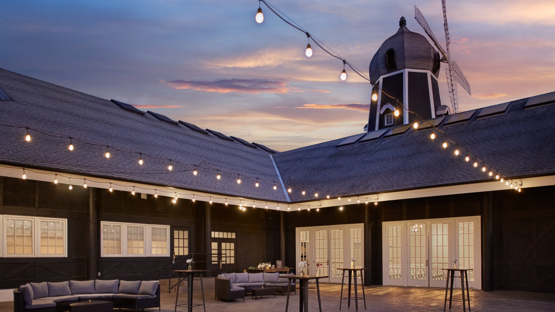 Carlsbad Windmill Palm Courtyard outdoor cocktail hour with string lights and sunset backdrop.