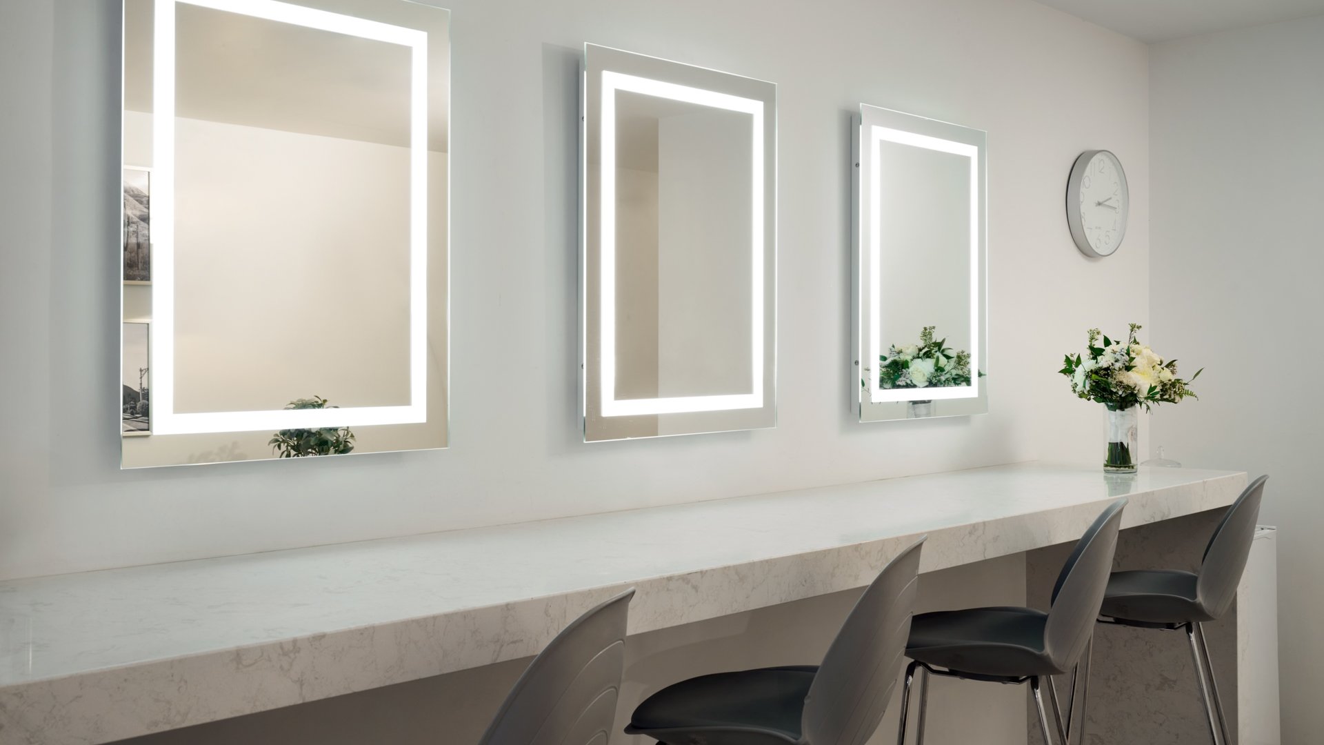 The Clayton House bridal suite in Scottsdale, Arizona, with illuminated vanity mirrors, marble countertop, and modern gray chairs — the perfect space for wedding preparation and photos.