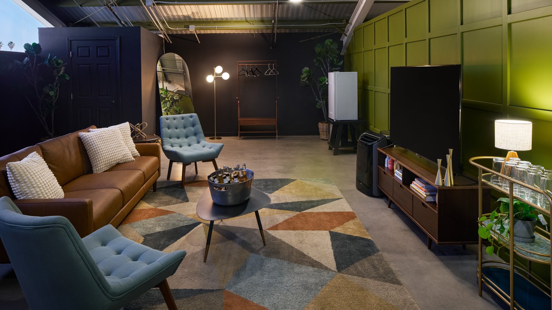 Wedding lounge suite at The Clayton House in Scottsdale, Arizona, featuring modern leather and blue seating, geometric rug, greenery, and a relaxed atmosphere ideal for pre-ceremony gatherings.