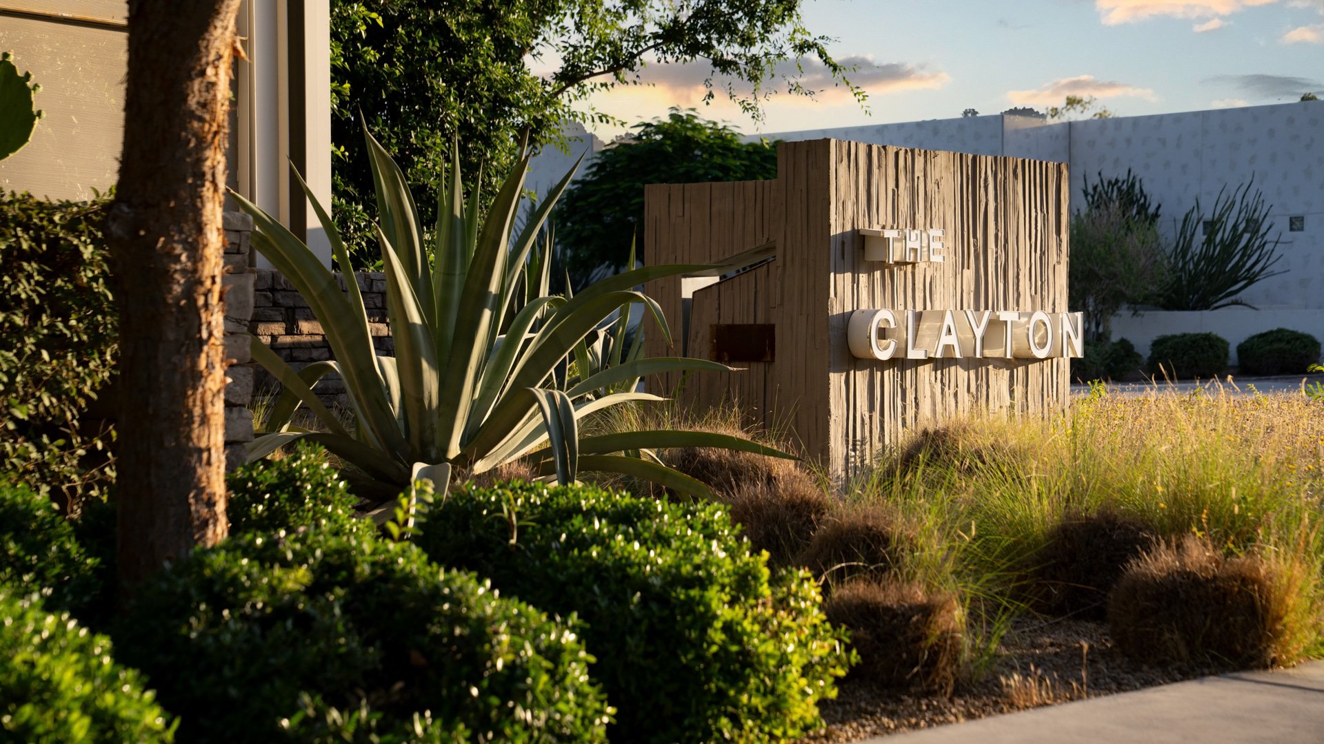 Close-up view of The Clayton House exterior in Scottsdale, AZ, highlighting modern architecture, desert landscaping, and the venue’s signature signage bathed in golden hour sunlight.
