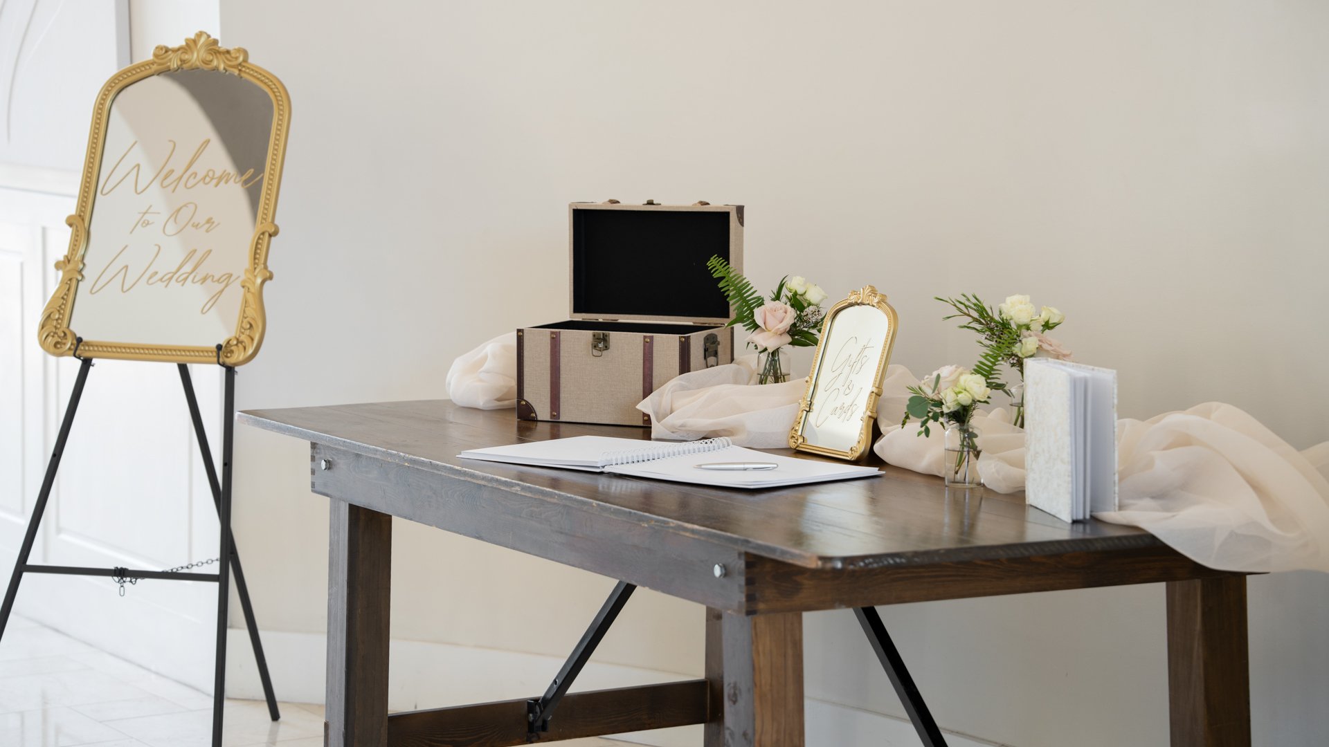 Wedding welcome table at Colby Falls in Arizona with guestbook, floral décor, gold mirror welcome sign, and gift card box.