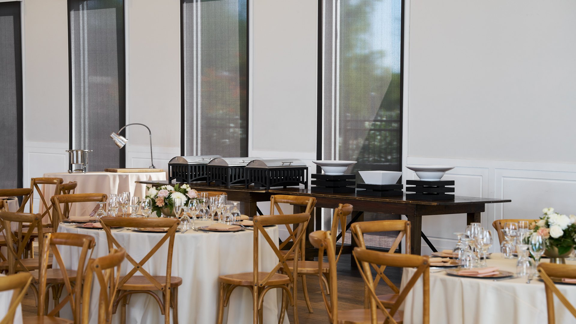 Buffet station setup inside Colby Falls Grand Hall Arizona, with banquet tables, chafing dishes, and rustic wood reception chairs.