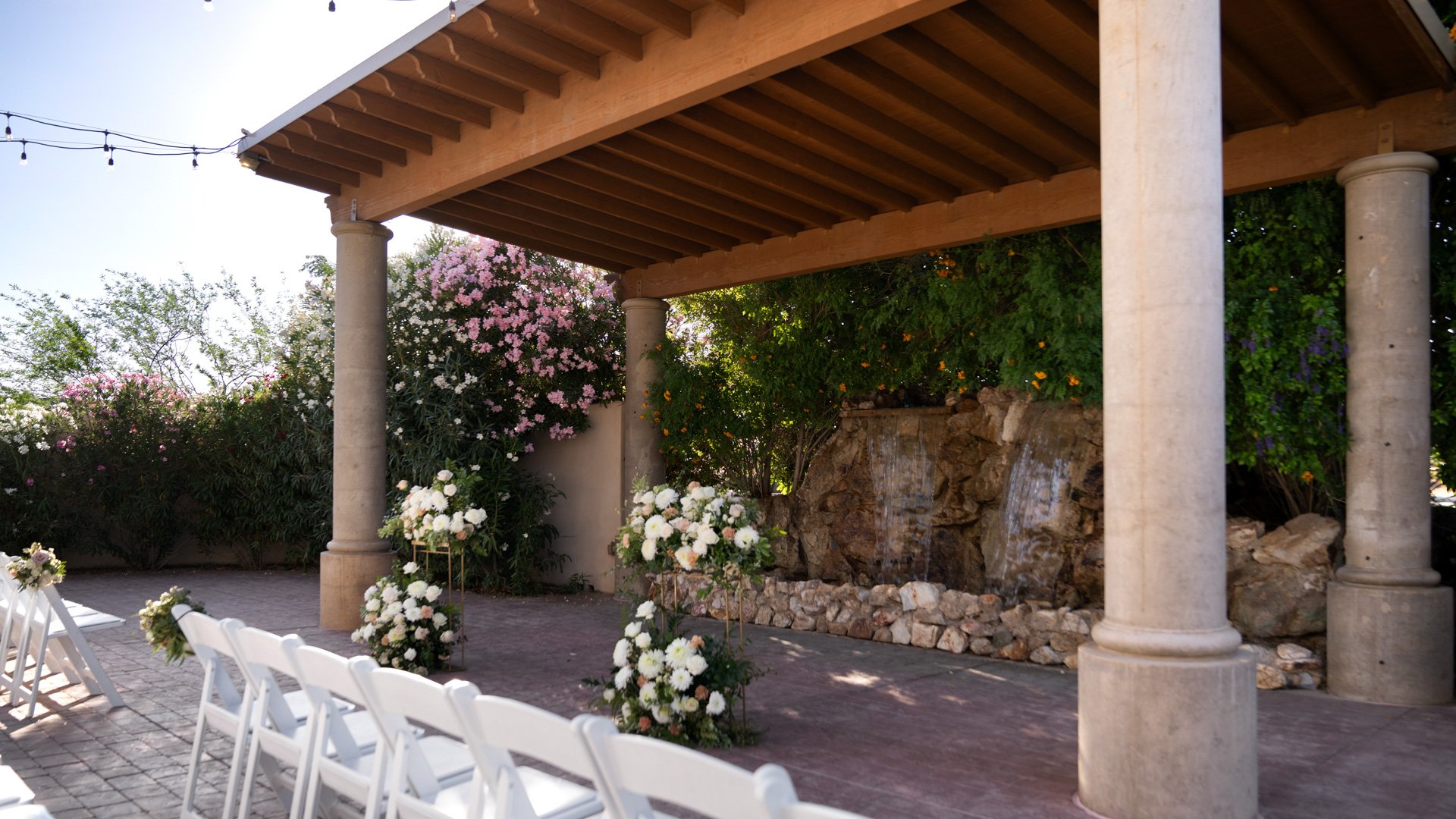 Grand Waterfall ceremony space at Colby Falls Arizona featuring stone pillars, cascading waterfall, floral arrangements, and guest seating.
