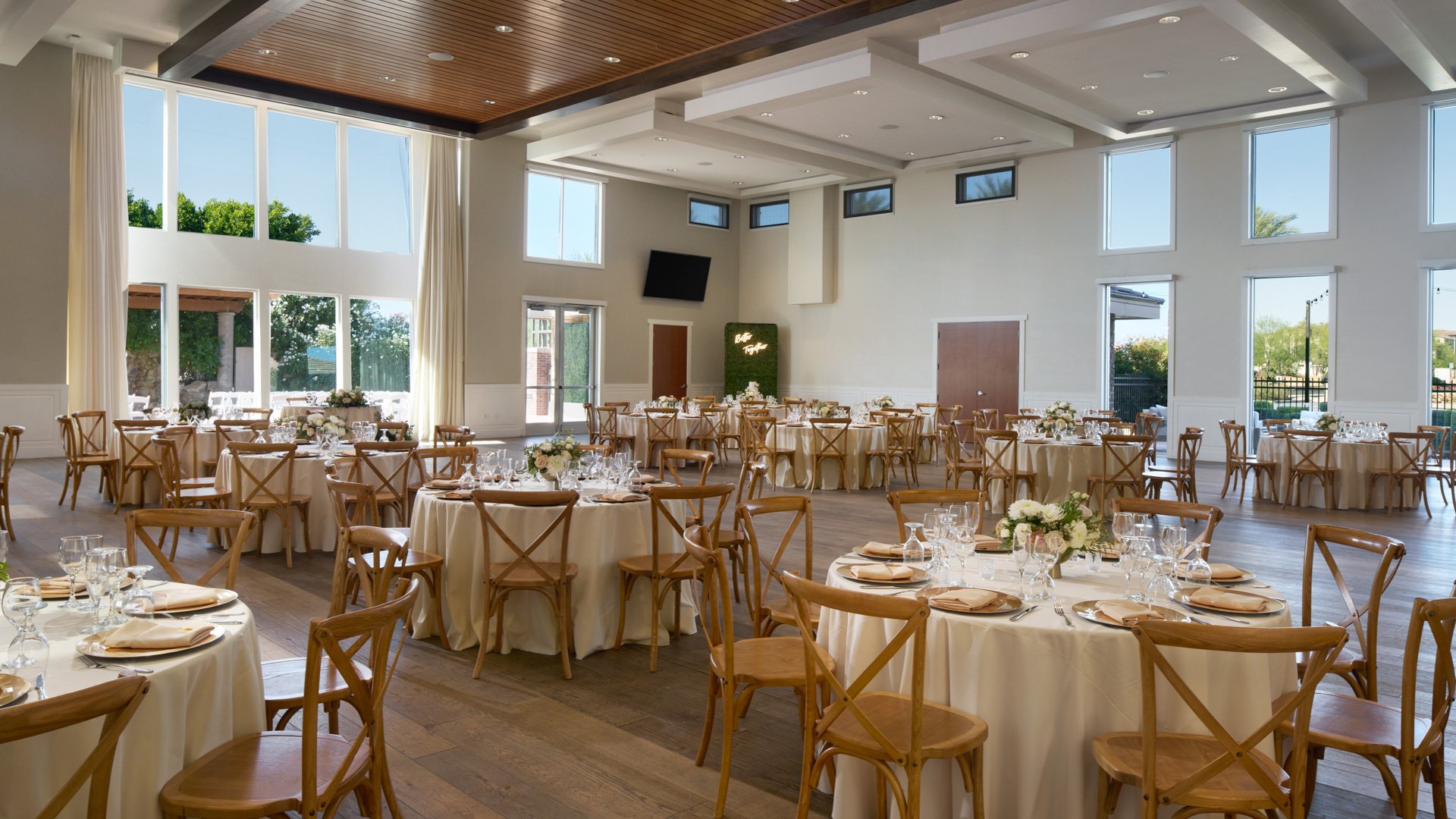 Grand Hall at Colby Falls in Arizona decorated for a wedding reception with round tables, rustic chairs, and natural light through tall windows.
