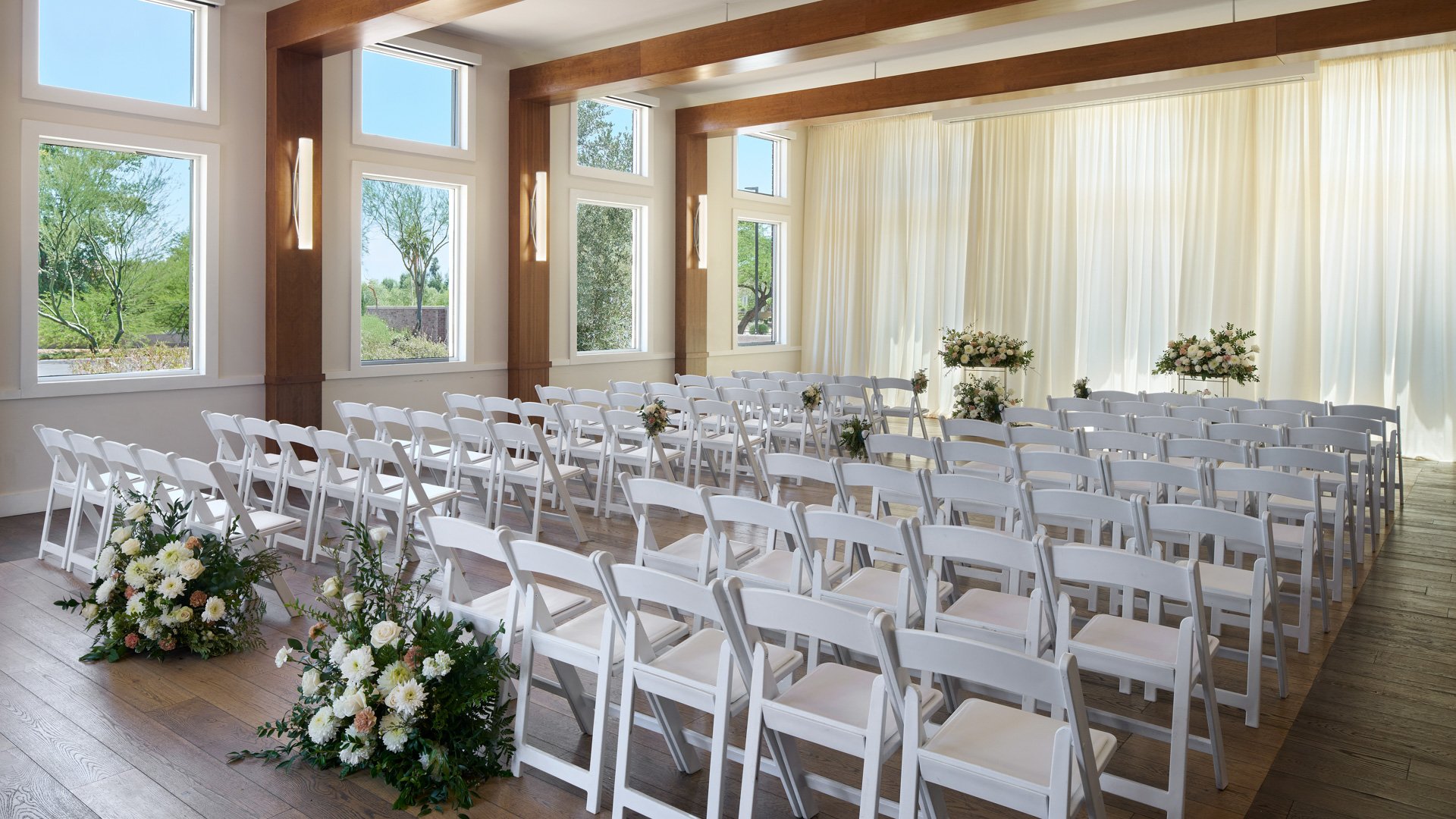 Indoor ceremony at Colby Falls Arizona in the Southwest Room with elegant drapery, greenery, and floral aisle markers for a modern wedding