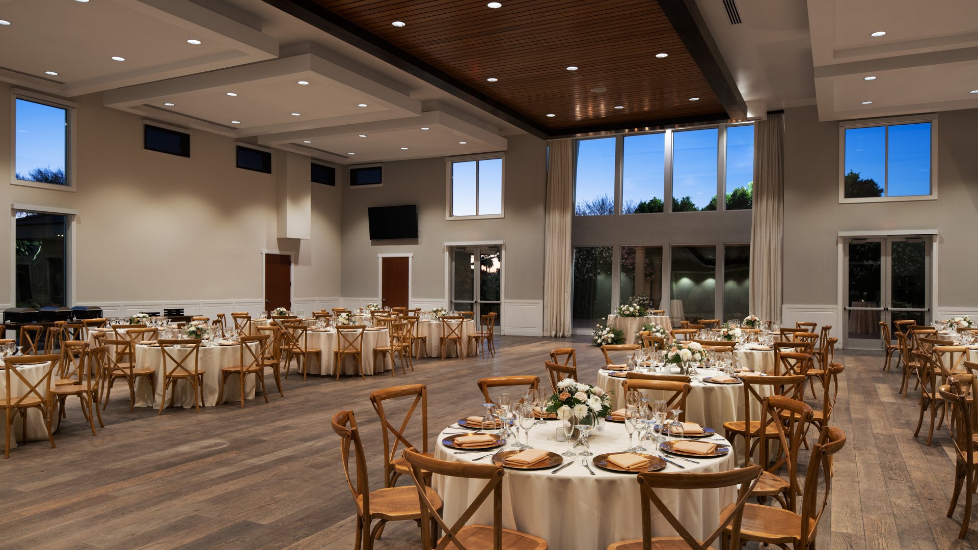 Evening reception at Colby Falls Grand Hall in Arizona featuring round banquet tables, rustic wooden chairs, and romantic floral centerpieces.