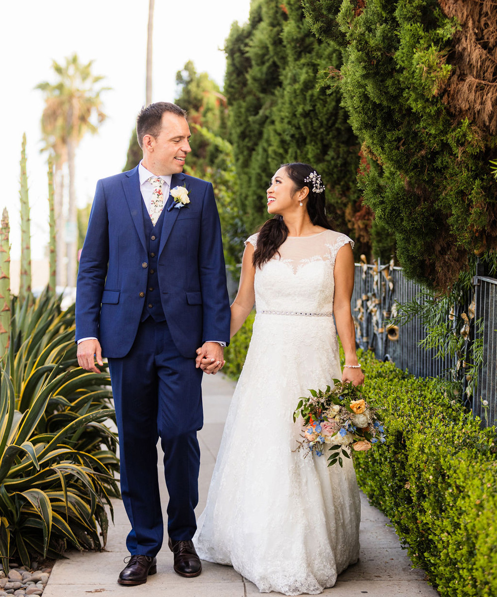couple walking down sidewalk with greenery - Cuvier Club by Wedgewood Weddings