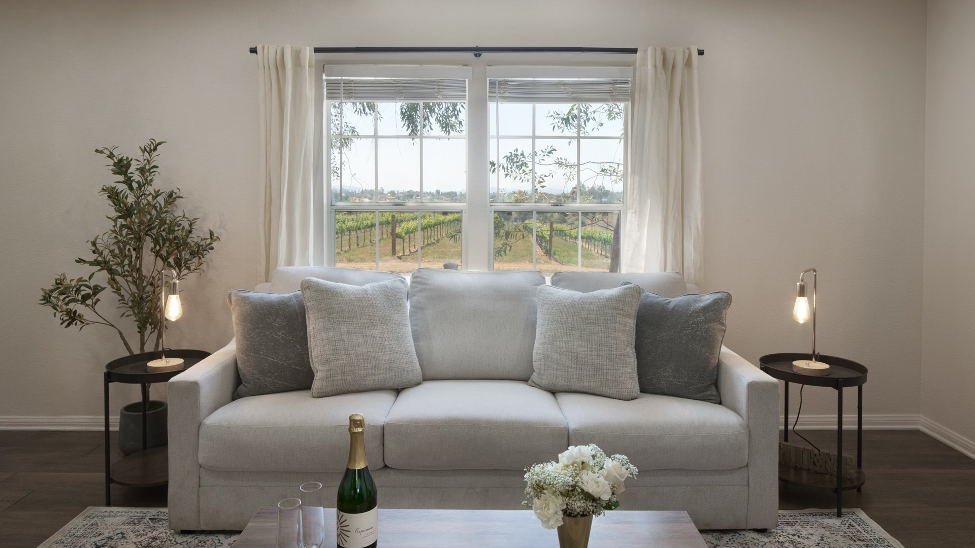 Cozy Studio Suite at Danza del Sol Winery in Temecula, CA, with vineyard view window, modern sofa seating, and champagne for bridal preparations.