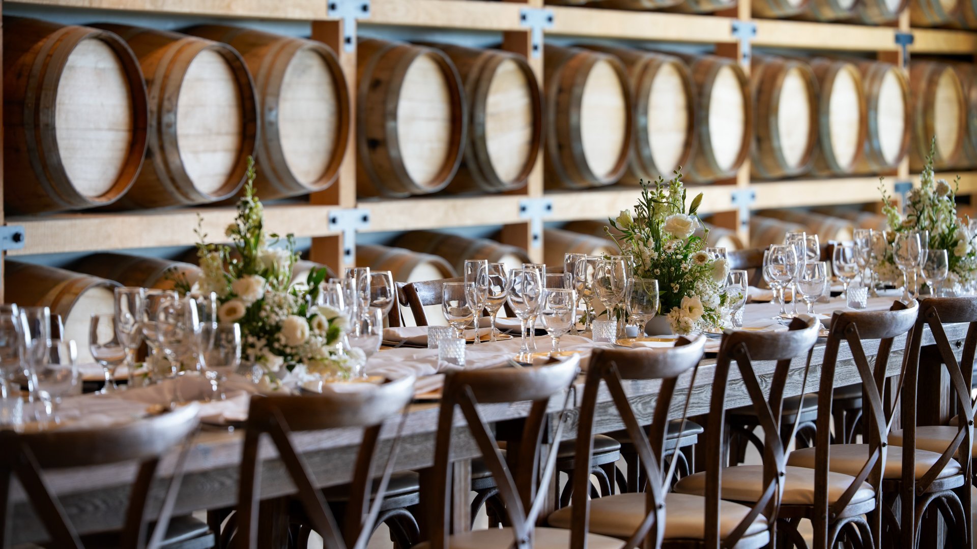 Detailed wedding tablescape in the Barrel Room at Danza del Sol Winery in Temecula, CA, featuring floral arrangements, elegant place settings, and wine barrel backdrop.