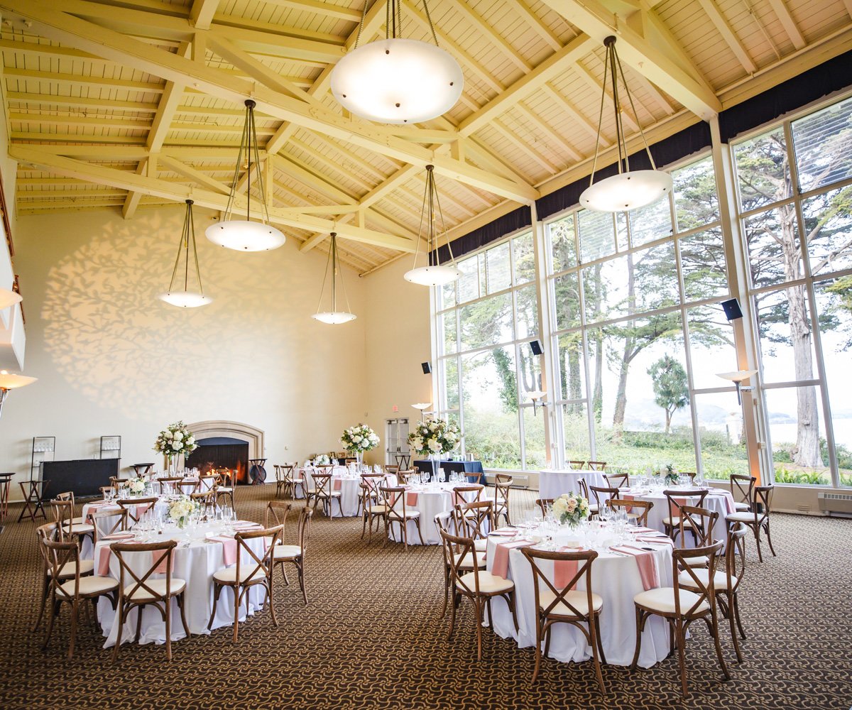 Spacious reception ballroom with white linens and pink napkins along with Bay area views - Golden Gate Club at the Presidio - Wedgewood Weddings - 1