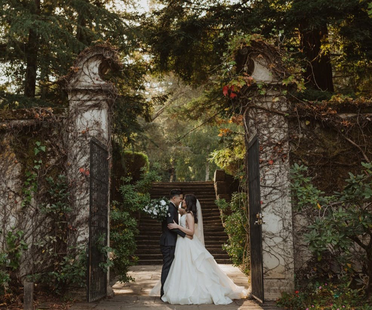 Couple posing in front of gates with greenery - Hacienda de las Flores by Wedgewood Weddings