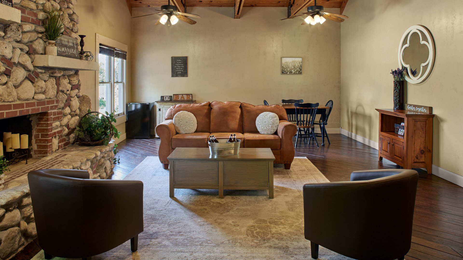Groom’s suite at the Hofmann Ranch Farm House with a cozy stone fireplace, leather sofa, and rustic wood décor.