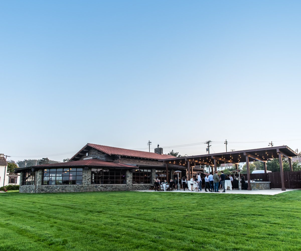 Outdoor patio with bistro lights and a vast green event lawn - Log Cabin at the Presidio - Wedgewood Weddings