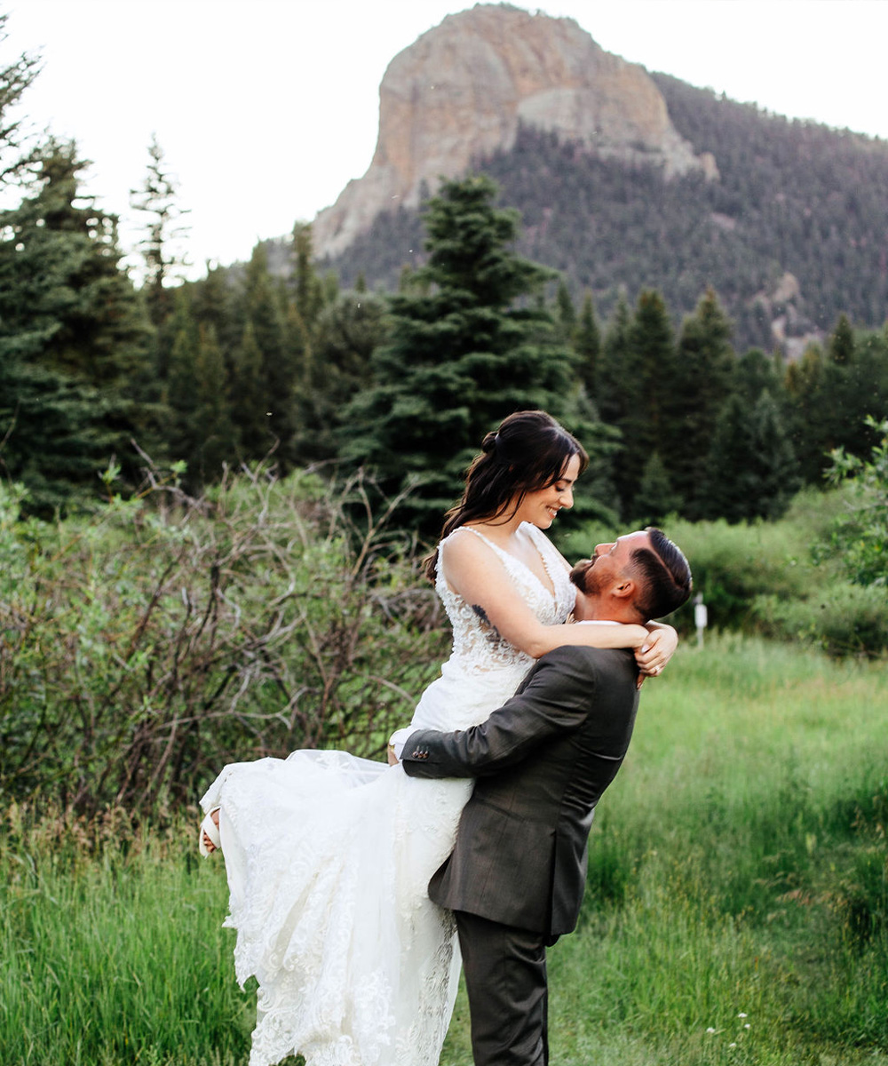 Groom lifting bride in front of mountains - Mountain View Ranch by Wedgewood Weddings
