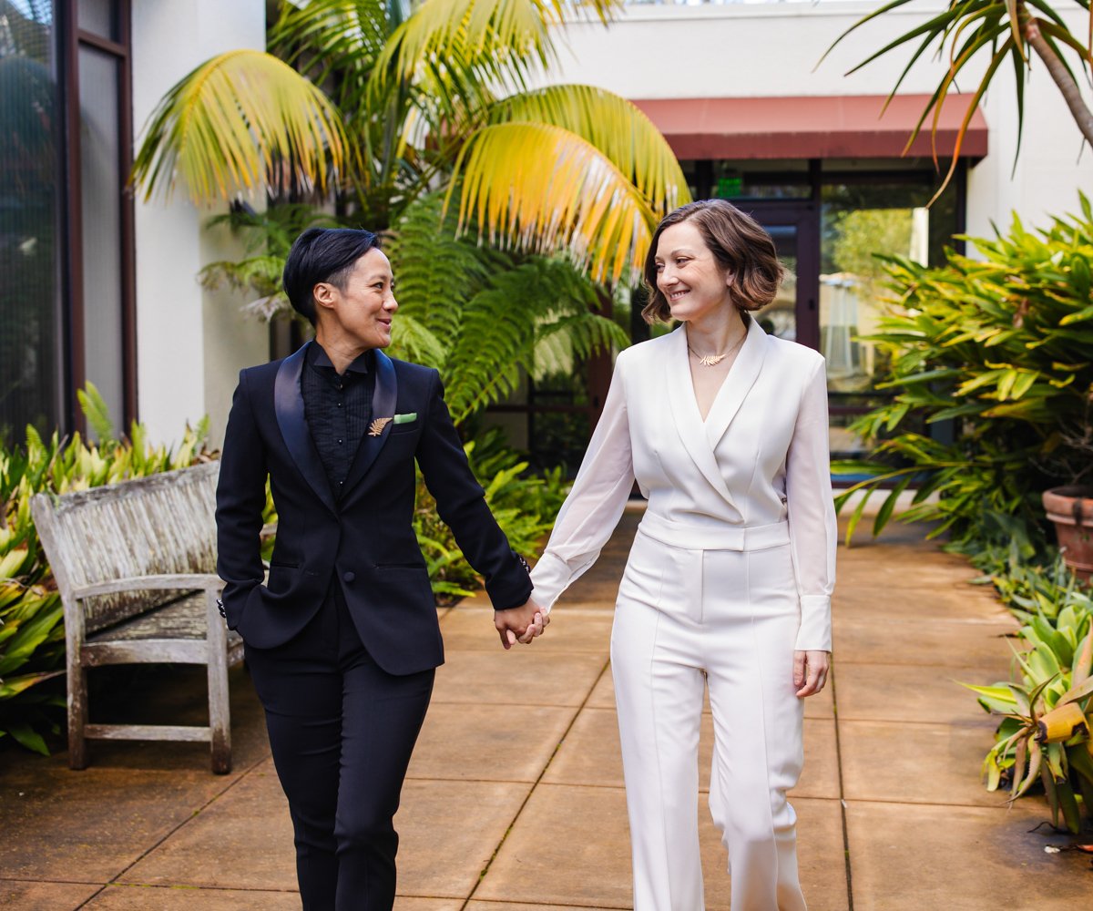 Bride and bride walking hand in hand through the Hardie Courtyard - LGBTQ wedding - Officers Club at the Presidio - Wedgewood Weddings - 2