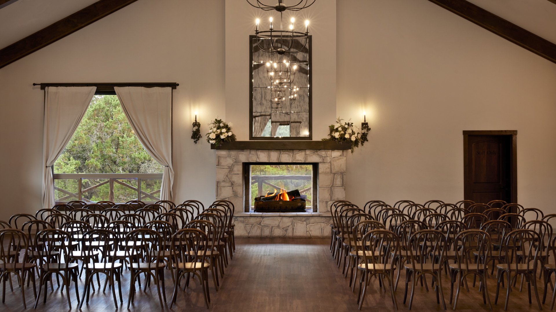 Indoor wedding ceremony setup at Scenic Springs Grand Ballroom in Helotes, TX, with rows of chairs facing a fireplace altar.