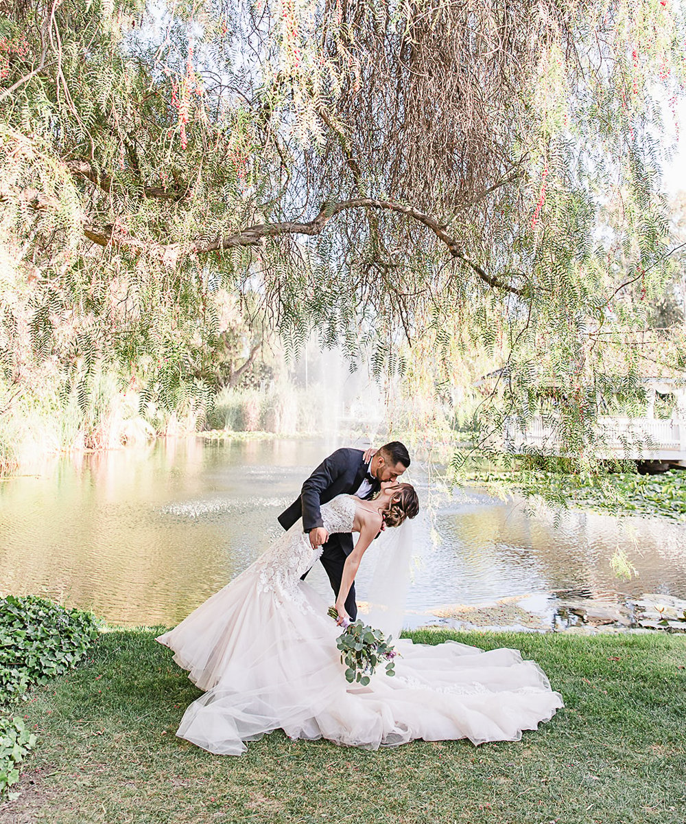 Couple kissing in front of pond at The Orchard