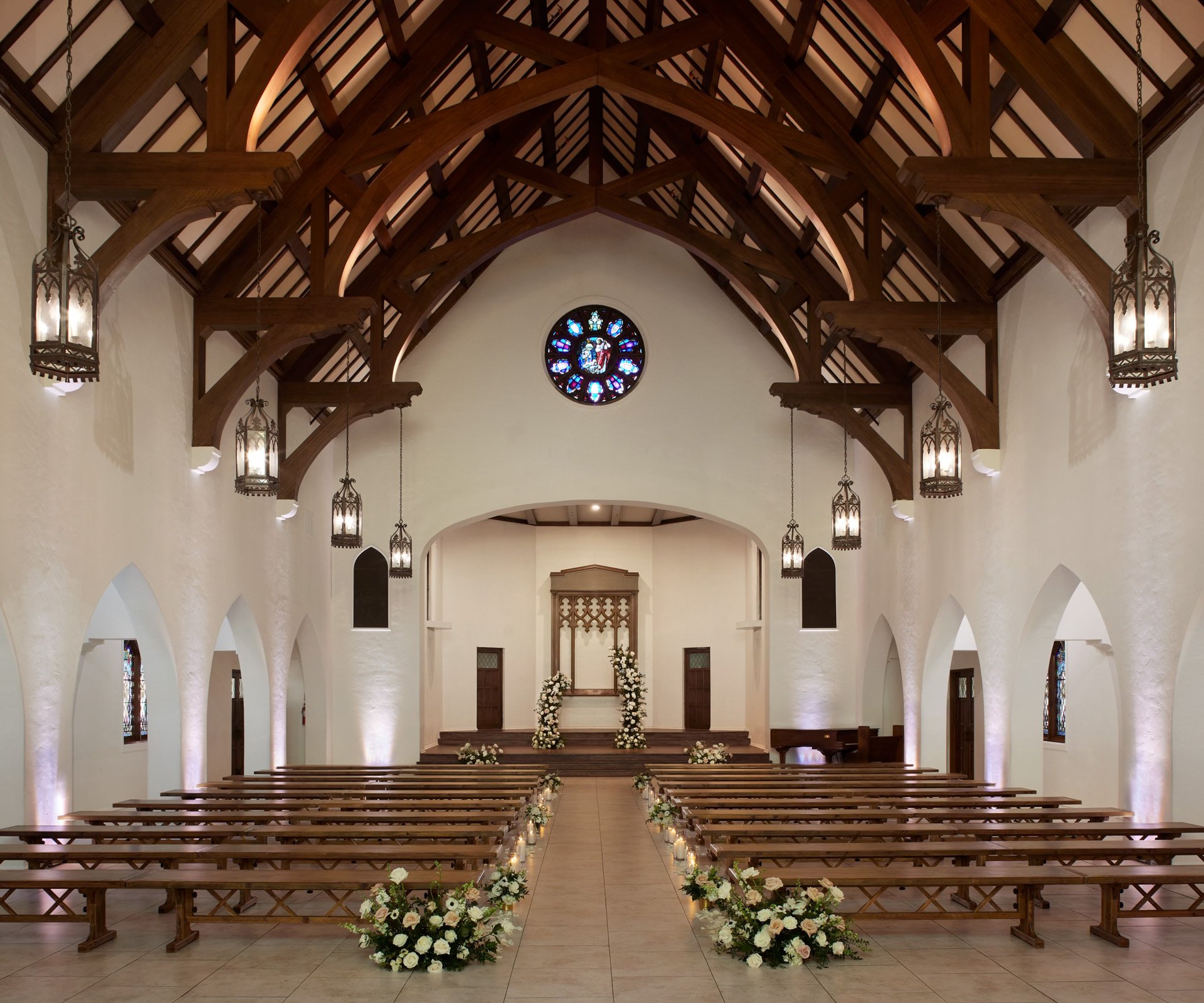 Elegant wedding ceremony setup in The Sanctuary Cathedral, Long Beach, with rose window and floral aisle arrangements.