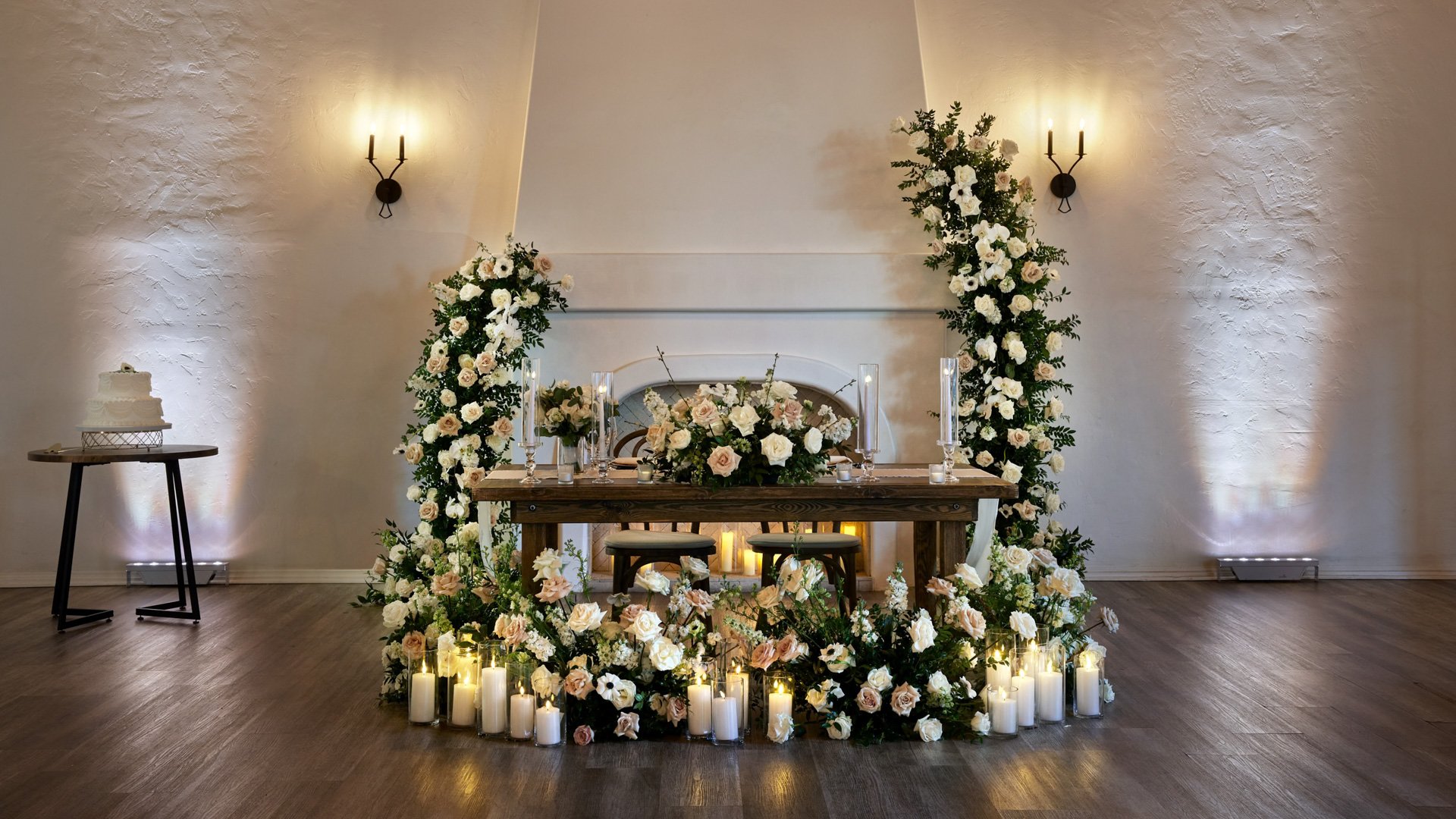 Sweetheart table in The Sanctuary’s Grand Hall, Long Beach, surrounded by lush florals and candles for a romantic wedding reception.