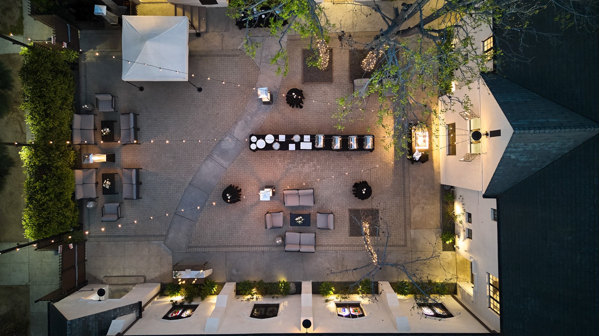Aerial view of The Sanctuary courtyard in Long Beach set for a wedding cocktail hour with lounge seating and string lights.