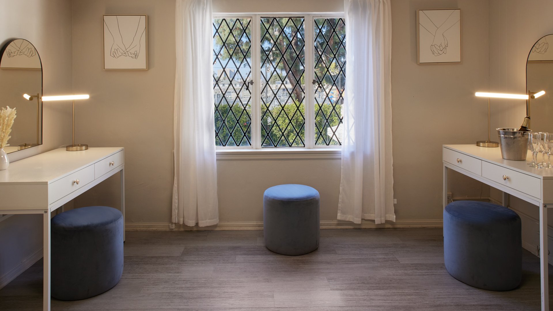 Bright wedding suite vanity area at The Sanctuary in Long Beach with matching mirrors, seating, and diamond-pane windows.