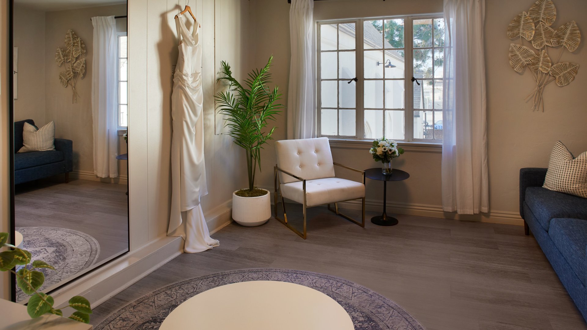 Bridal dressing room at The Sanctuary in Long Beach with wedding gown on display, full-length mirror, and seating area.