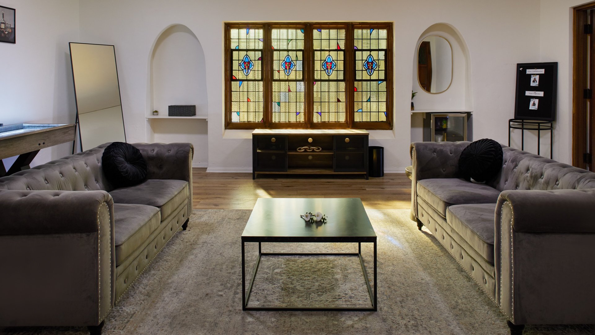 Groom’s lounge suite at The Sanctuary in Long Beach with leather seating, game table, and stained glass windows.