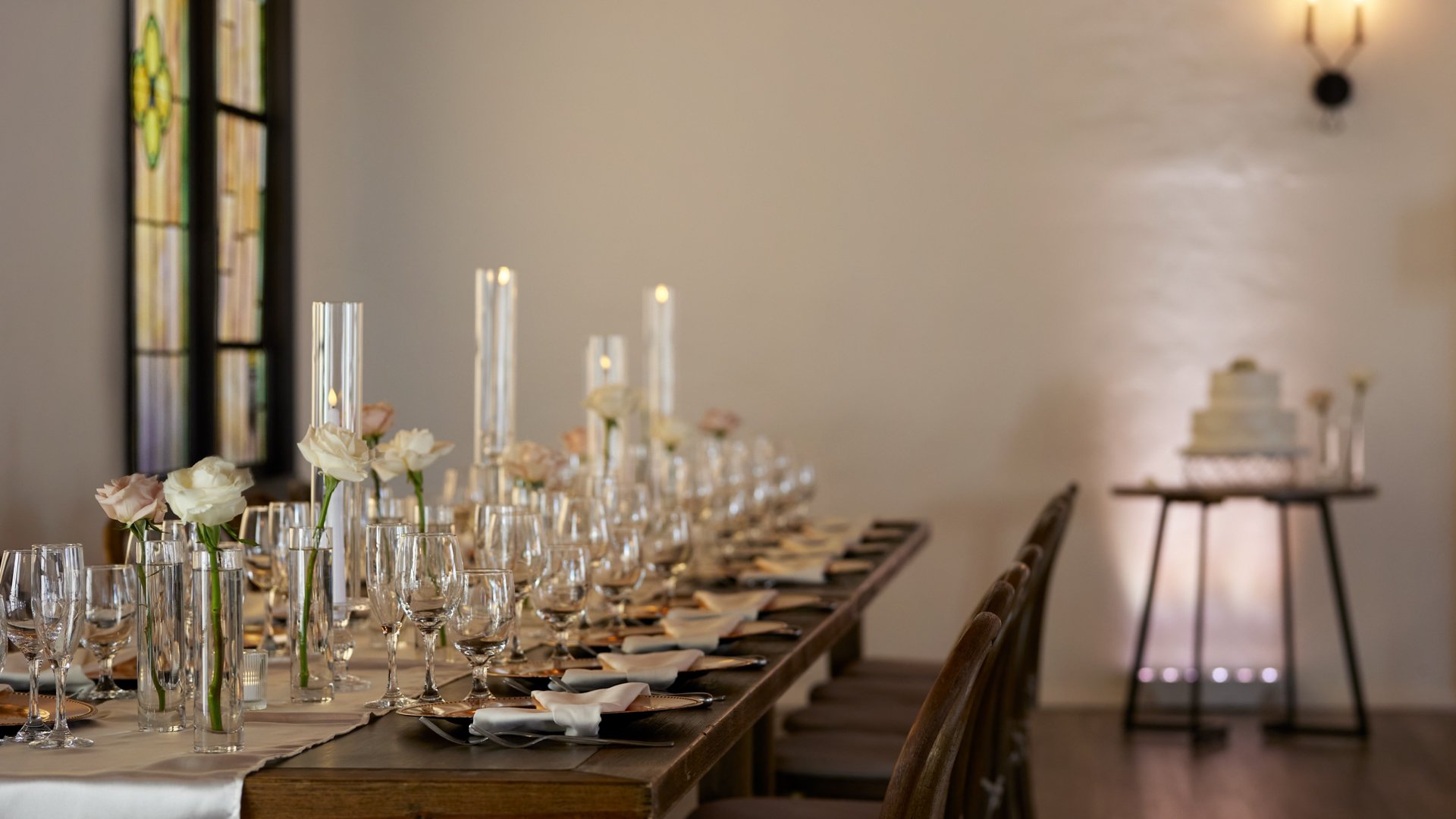 Wedding table place setting in The Sanctuary Grand Hall, Long Beach, with gold charger plates, glassware, and white florals.