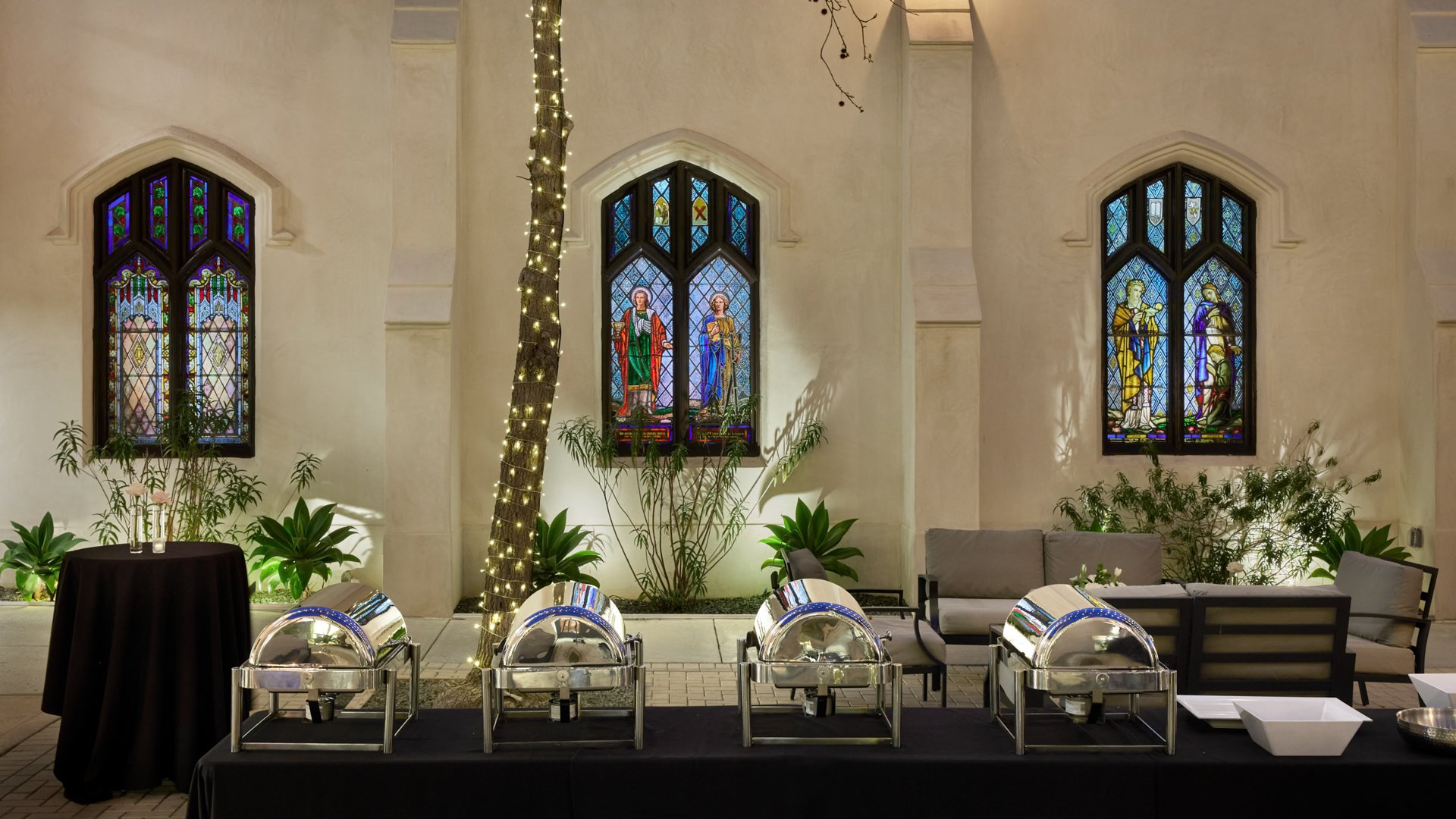 Wedding table at The Sanctuary in Long Beach decorated with white roses, greenery, and glowing candles.