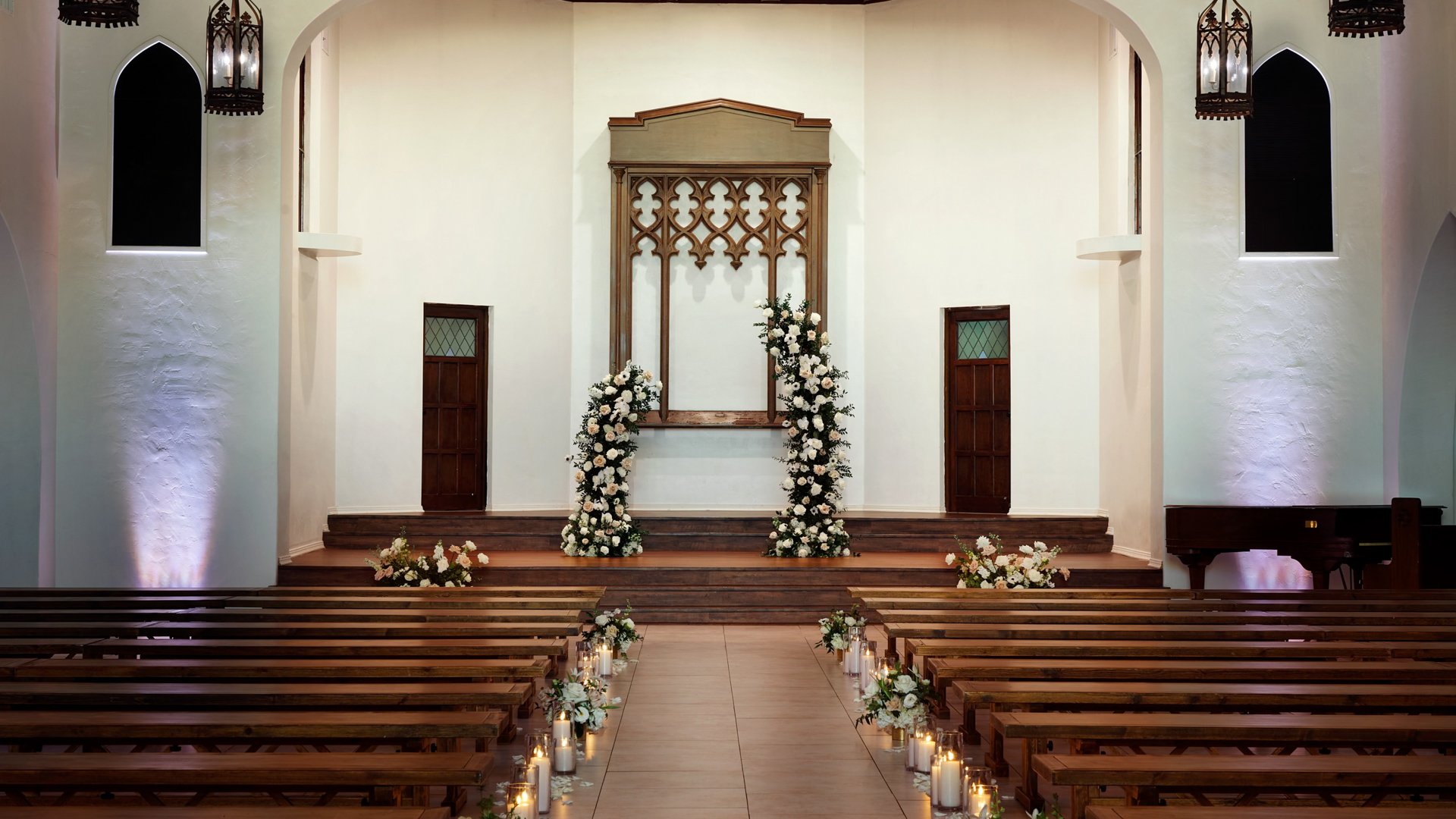 Close-up of the wedding altar at The Sanctuary Cathedral in Long Beach, adorned with white floral arches and candlelit aisle.