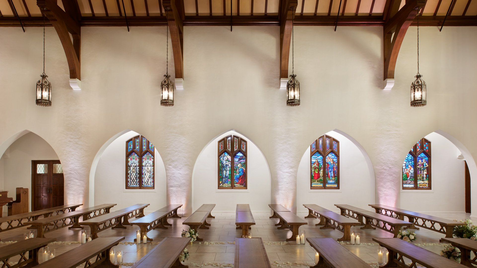 Side view of The Sanctuary Cathedral in Long Beach showcasing stained glass windows, wooden pews, and romantic wedding décor.
