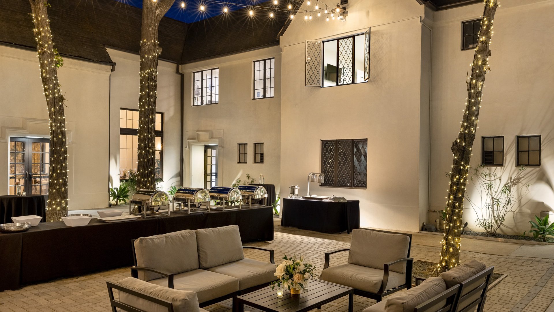 Outdoor courtyard at The Sanctuary in Long Beach decorated with string lights, cocktail tables, and lounge seating for wedding guests.