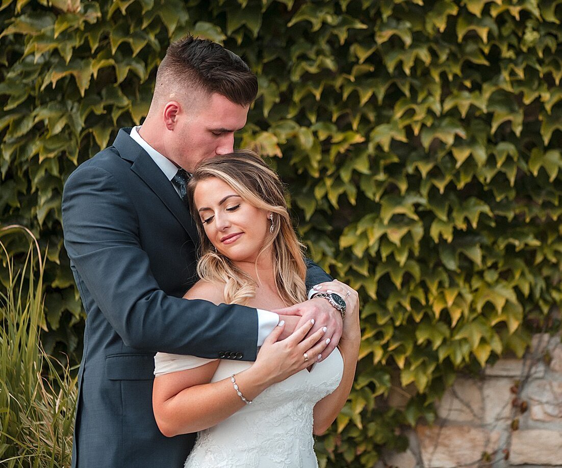 Bride-and-Groom-Embrace-in-front-of-Ivy-wall---Winchester-Estate-by-Wedgewood-Weddings