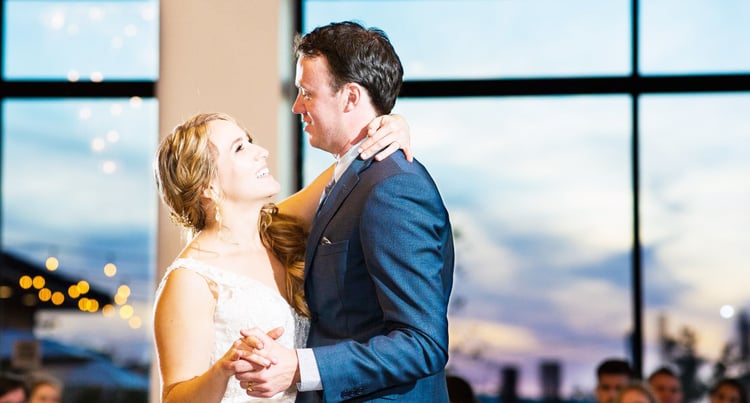 A BRIDE AND GROOM ENJOY FLOOR-TO-CEILING SUNSET VIEWS FROM THE BALLROOM AT UNIVERSITY CLUB