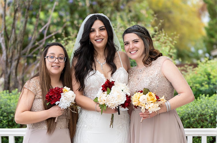 The bride smiling with her bridesmaids, all holding faux flower bouquets.